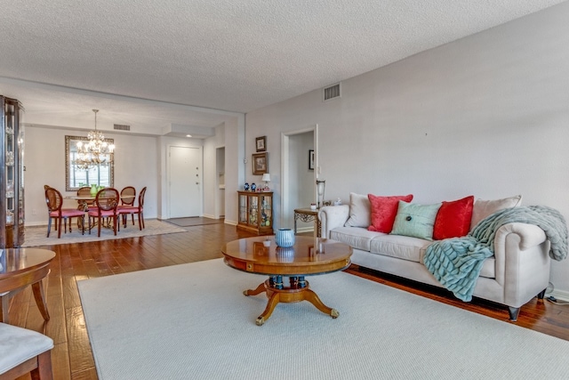 living room with an inviting chandelier, hardwood / wood-style flooring, and a textured ceiling