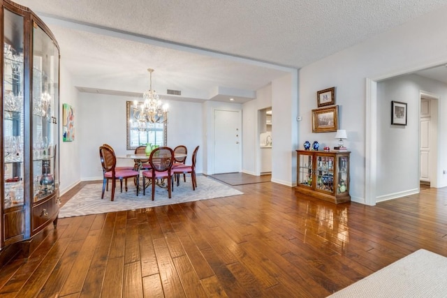 dining room with dark wood-style floors, a textured ceiling, baseboards, visible vents, and an inviting chandelier