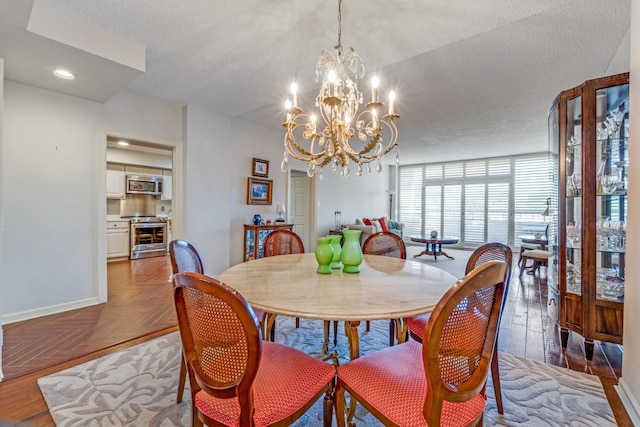 dining room featuring parquet flooring, a chandelier, and a textured ceiling