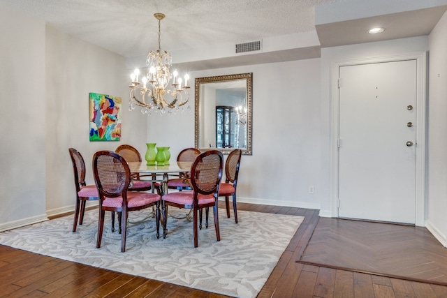 dining space with wood-type flooring, a chandelier, and a textured ceiling