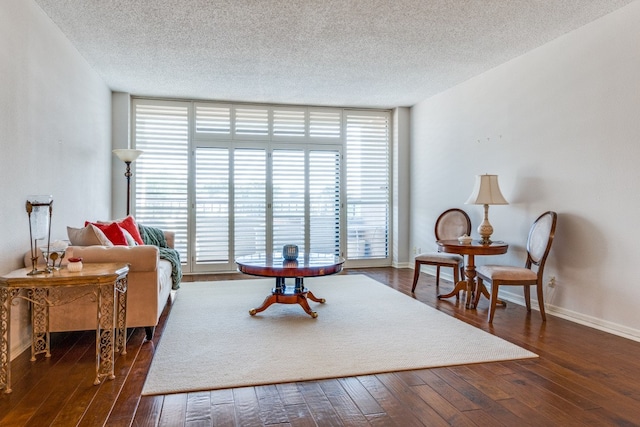 sitting room featuring plenty of natural light, floor to ceiling windows, dark hardwood / wood-style floors, and a textured ceiling