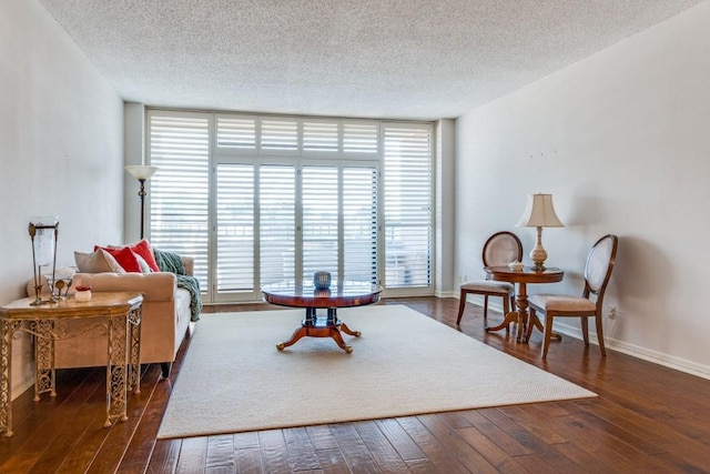 living area with baseboards, hardwood / wood-style floors, and a textured ceiling