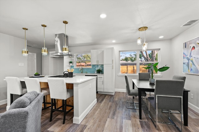 kitchen featuring wood-type flooring, island range hood, decorative light fixtures, white cabinets, and a center island