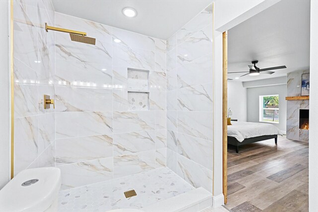 bedroom featuring wood-type flooring, a high end fireplace, and ceiling fan