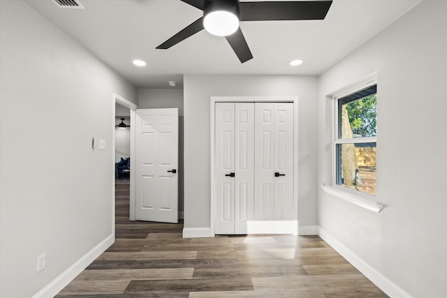 unfurnished bedroom with ceiling fan, a closet, and dark hardwood / wood-style flooring