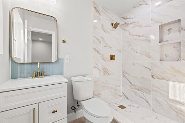 bathroom with a tile shower, vanity, and toilet