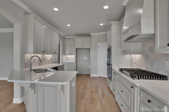 kitchen featuring backsplash, custom range hood, sink, light hardwood / wood-style flooring, and white cabinets