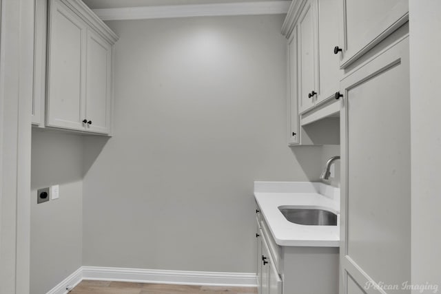 washroom featuring electric dryer hookup, light hardwood / wood-style floors, cabinets, and sink