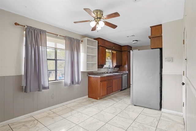 kitchen with appliances with stainless steel finishes, ceiling fan, wooden walls, and sink