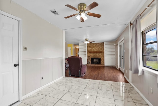 unfurnished living room with a fireplace, ceiling fan, and built in features