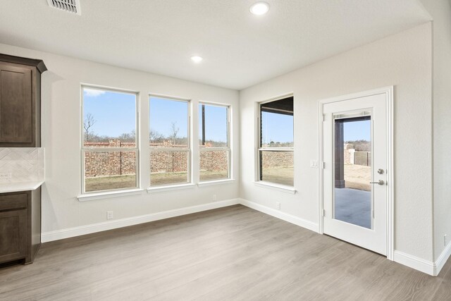 kitchen featuring premium range hood, white cabinetry, appliances with stainless steel finishes, light hardwood / wood-style floors, and decorative backsplash