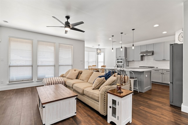 living room featuring dark wood-type flooring and ceiling fan