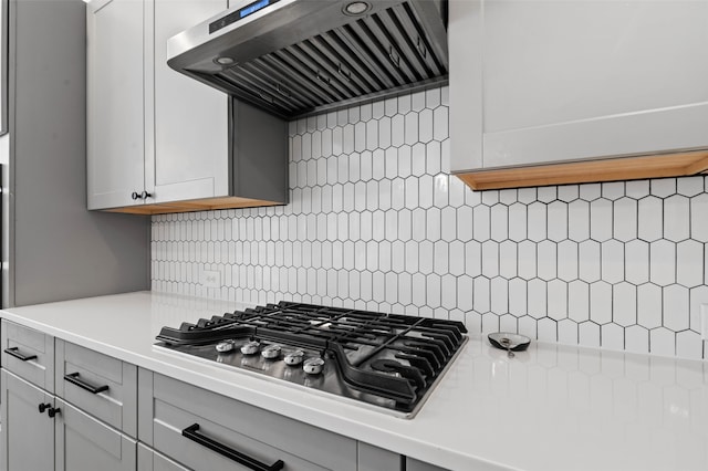 kitchen with extractor fan, decorative backsplash, white cabinets, and stainless steel gas cooktop