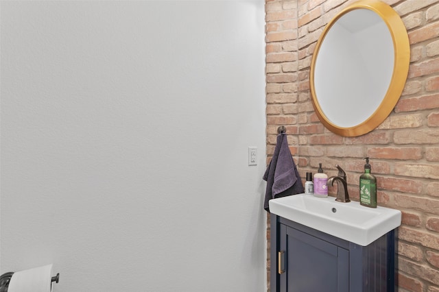 bathroom with vanity and brick wall