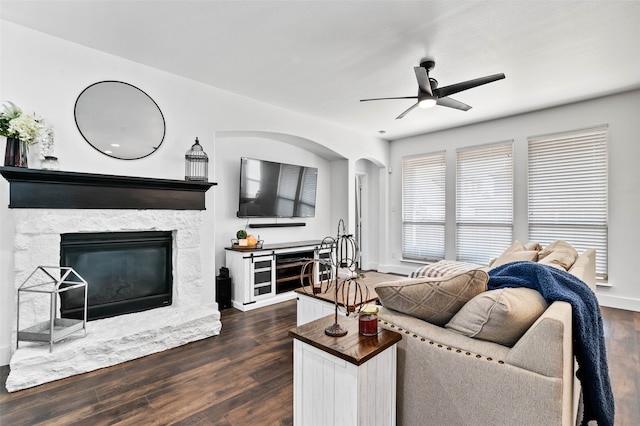 living room featuring dark wood-type flooring, ceiling fan, and a fireplace