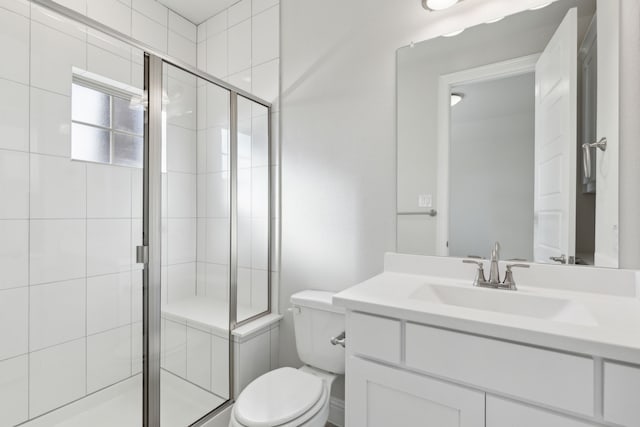 bathroom featuring vanity, toilet, and a shower with door