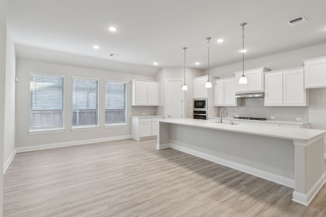 kitchen featuring pendant lighting, a spacious island, sink, white cabinetry, and stainless steel appliances