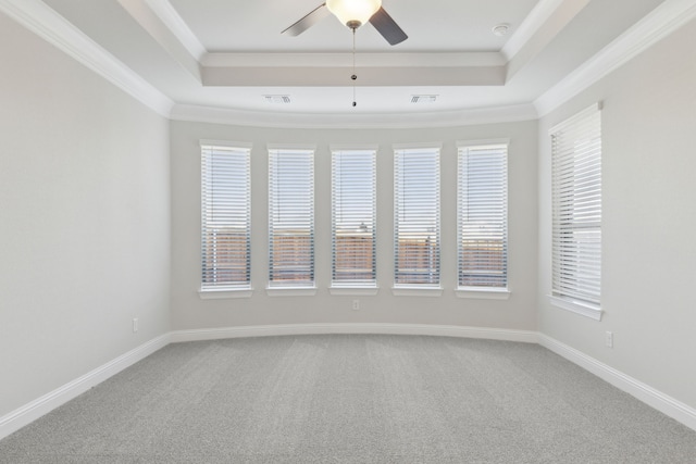 carpeted spare room with a tray ceiling, ceiling fan, a healthy amount of sunlight, and ornamental molding