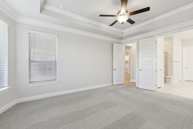 unfurnished bedroom featuring light carpet, a raised ceiling, crown molding, ensuite bath, and ceiling fan