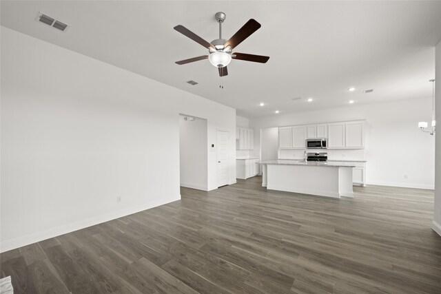 kitchen with light hardwood / wood-style flooring, hanging light fixtures, a center island with sink, white cabinets, and appliances with stainless steel finishes