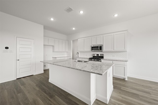 kitchen with appliances with stainless steel finishes, white cabinets, and an island with sink