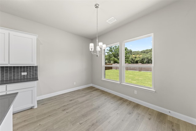 unfurnished dining area featuring light hardwood / wood-style flooring and a chandelier