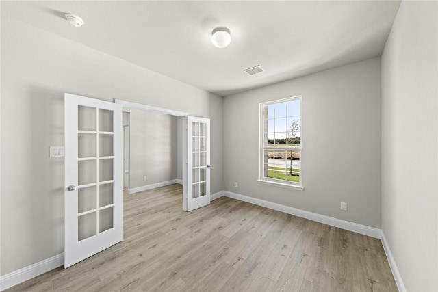 spare room featuring french doors and light wood-type flooring