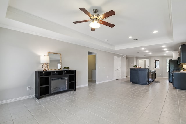 living room with ceiling fan, light tile patterned floors, a raised ceiling, ornamental molding, and a fireplace