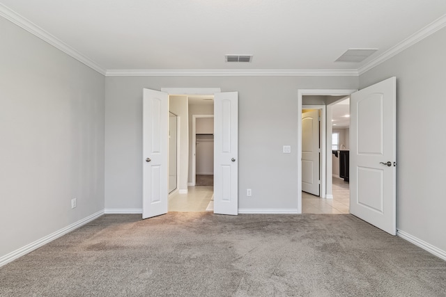 unfurnished bedroom featuring a spacious closet, crown molding, and light colored carpet