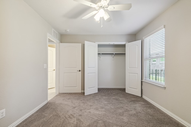 unfurnished bedroom with a closet, light colored carpet, and ceiling fan