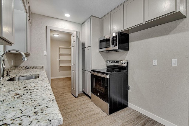 417 Lena Ln, Burleson, TX 76028 - kitchen with electric range, stainless steel microwave, light wood-type flooring, light stone counters, and a textured wall