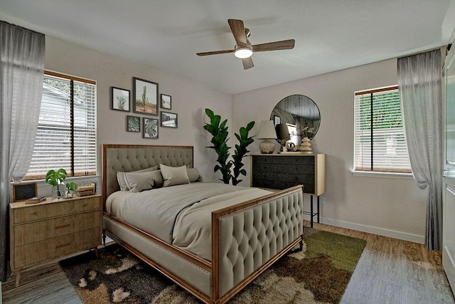 bedroom with baseboards, wood finished floors, ceiling fan, and multiple windows