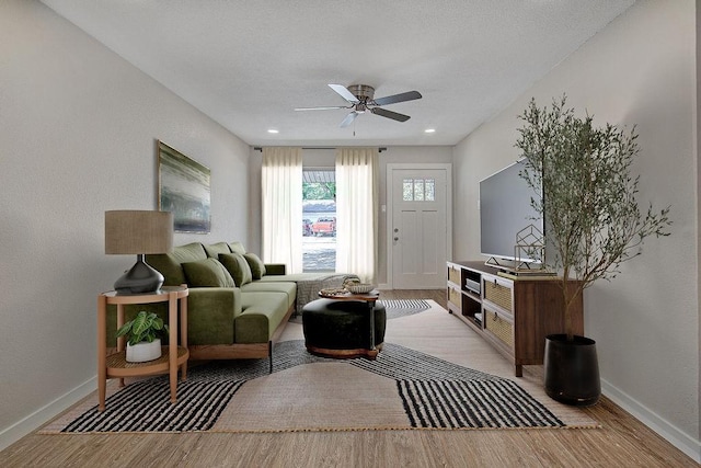 living area featuring baseboards, a ceiling fan, and light wood-style floors