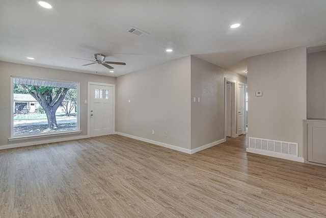 interior space featuring baseboards, a ceiling fan, light wood finished floors, and visible vents