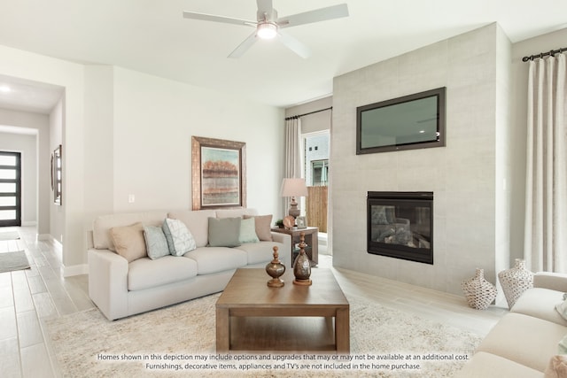 living room featuring ceiling fan, light hardwood / wood-style flooring, and a tile fireplace