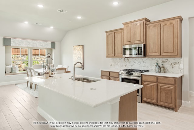 kitchen with an island with sink, stainless steel appliances, sink, and lofted ceiling