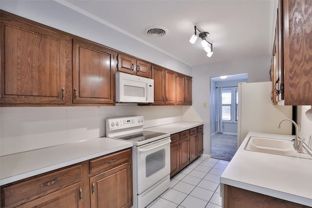 kitchen with light tile patterned floors, white appliances, and sink