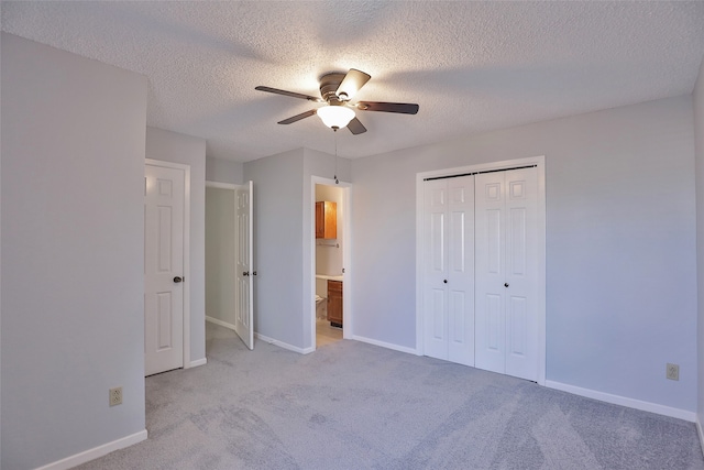 unfurnished bedroom featuring ceiling fan, a closet, light colored carpet, and a textured ceiling