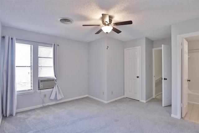 unfurnished bedroom with light carpet, connected bathroom, ceiling fan, and cooling unit