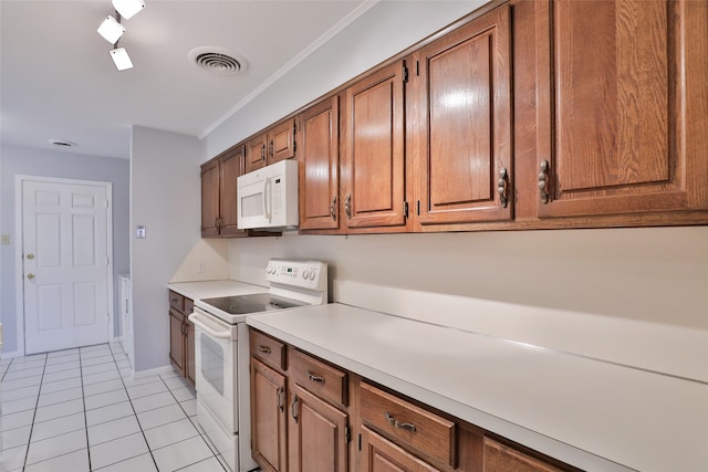 kitchen with crown molding, light tile patterned flooring, and white appliances