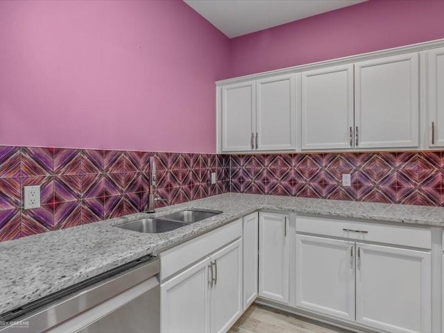 kitchen with light stone countertops, sink, white cabinetry, and stainless steel dishwasher