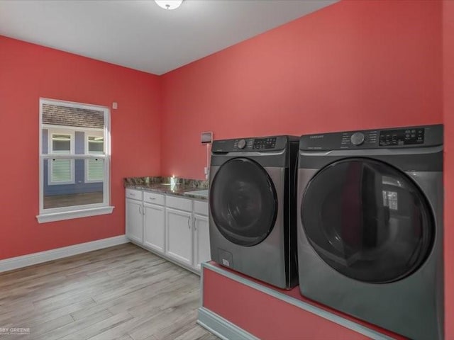 laundry area with light hardwood / wood-style floors, cabinets, and washing machine and clothes dryer