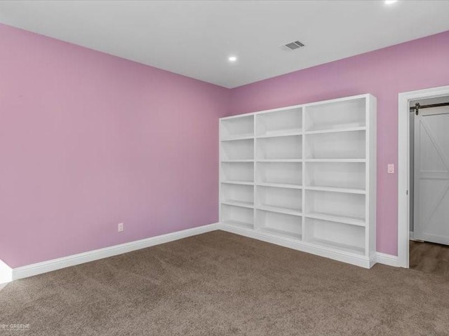 unfurnished bedroom featuring carpet floors and a barn door