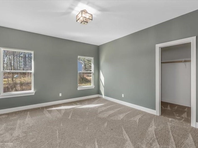 unfurnished bedroom featuring multiple windows, a closet, carpet, and a walk in closet