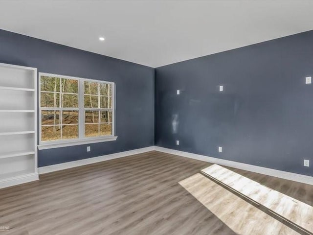 spare room with built in shelves and hardwood / wood-style flooring