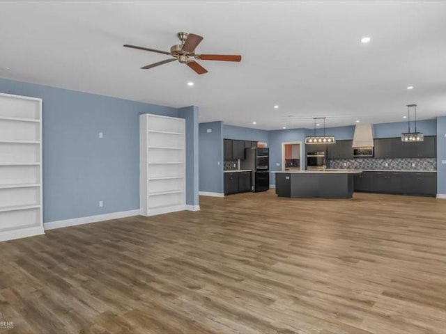 unfurnished living room featuring dark wood-type flooring and ceiling fan