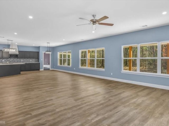 unfurnished living room featuring ceiling fan, plenty of natural light, and dark hardwood / wood-style flooring