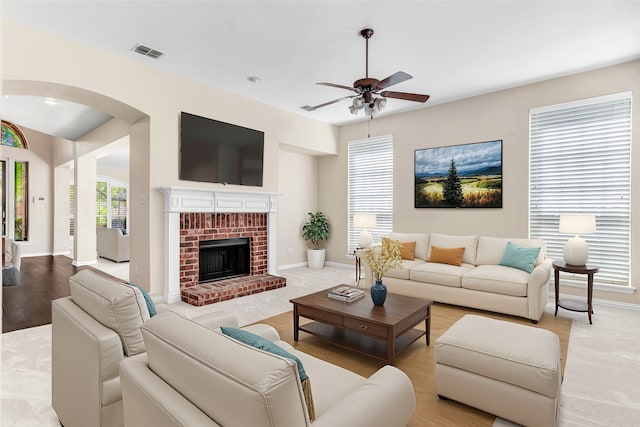 living room with ceiling fan, a fireplace, and light hardwood / wood-style floors