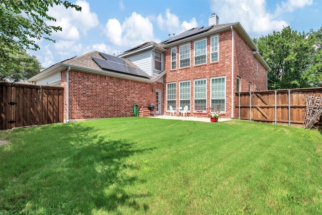 back of property with a patio, a lawn, and solar panels