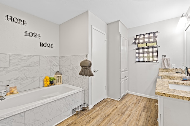 bathroom with vanity, a relaxing tiled tub, and wood-type flooring